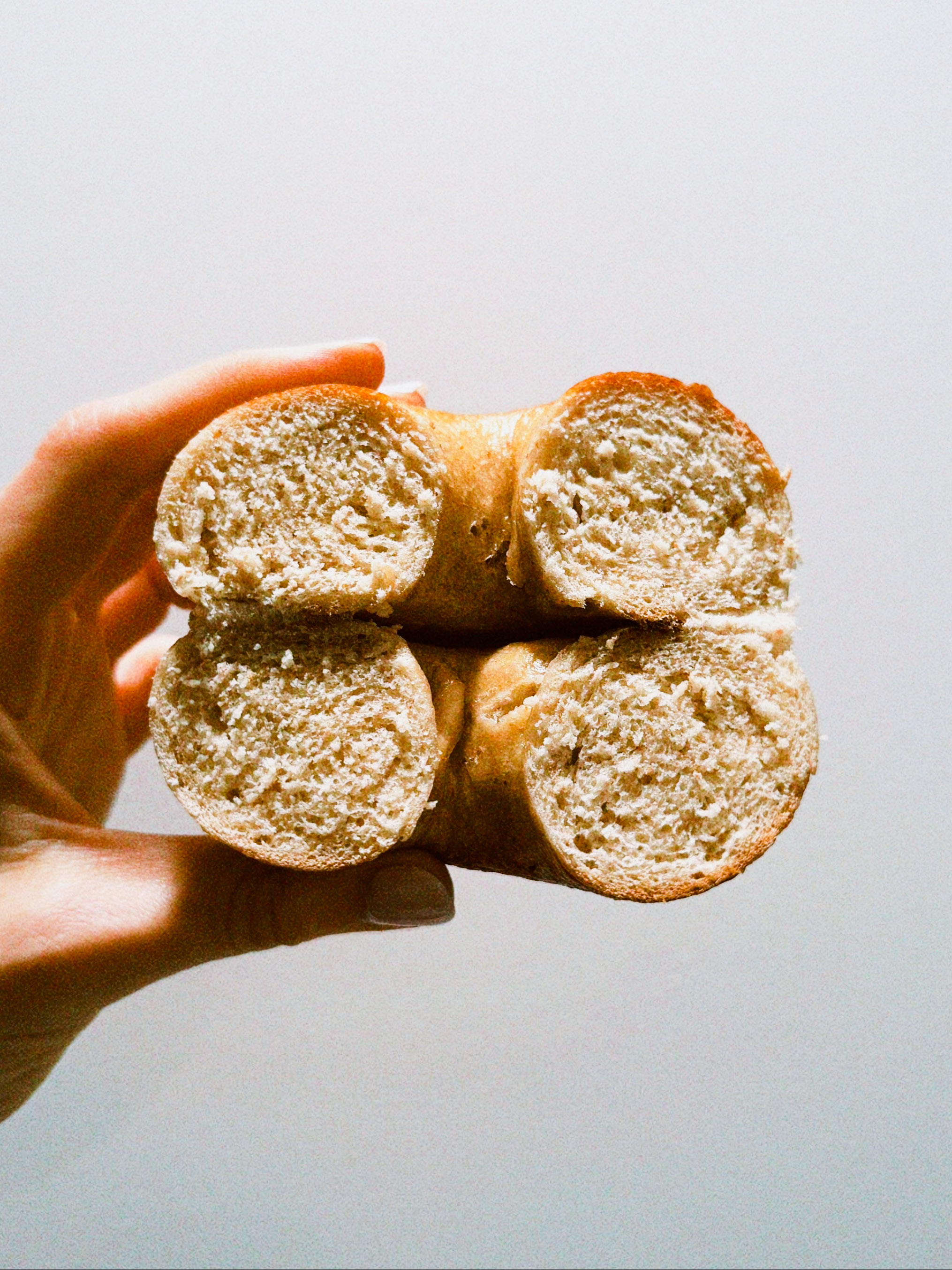 A freshly sliced bagel held in one hand